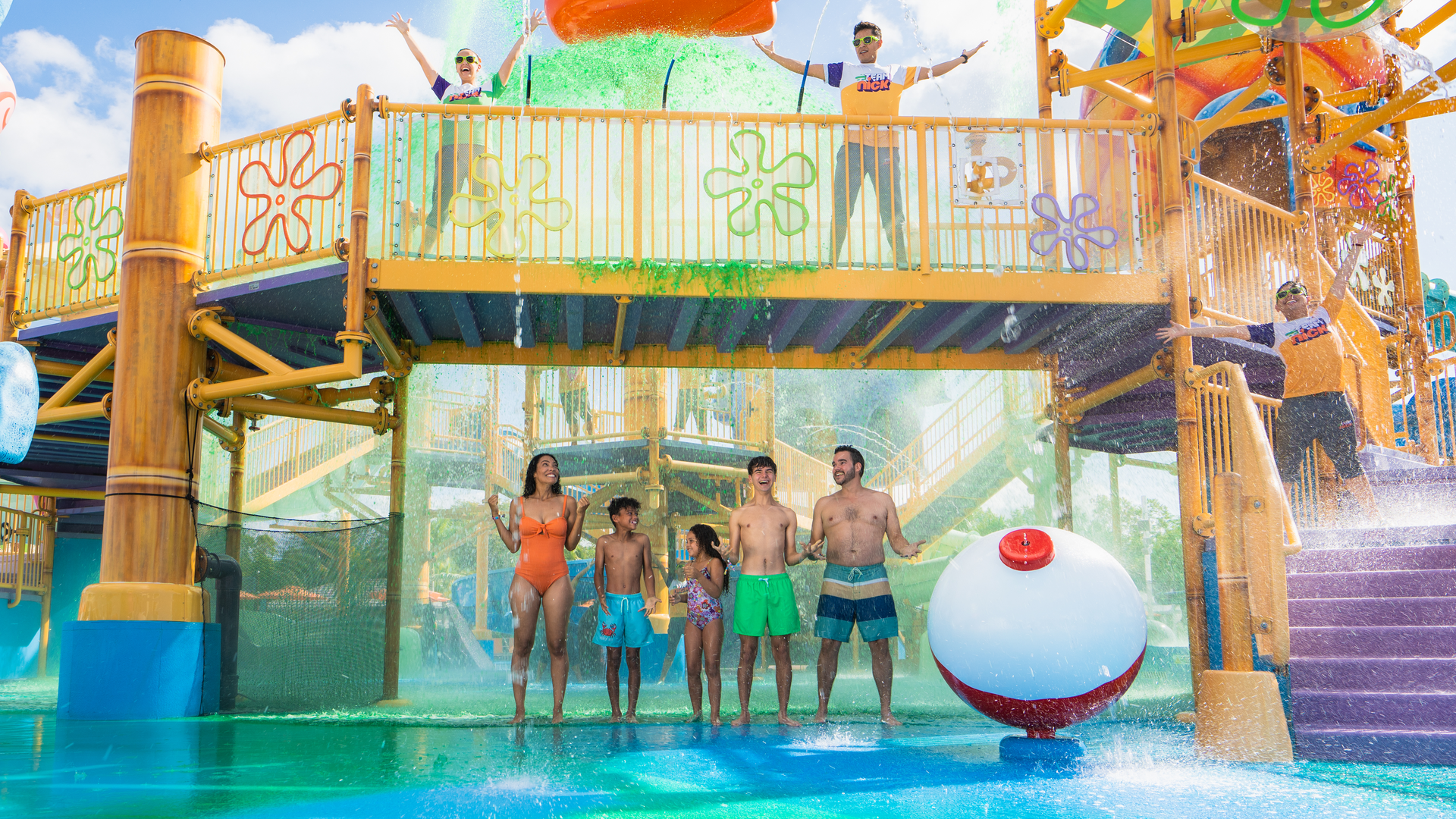A Group Of People Standing On A Water Slide