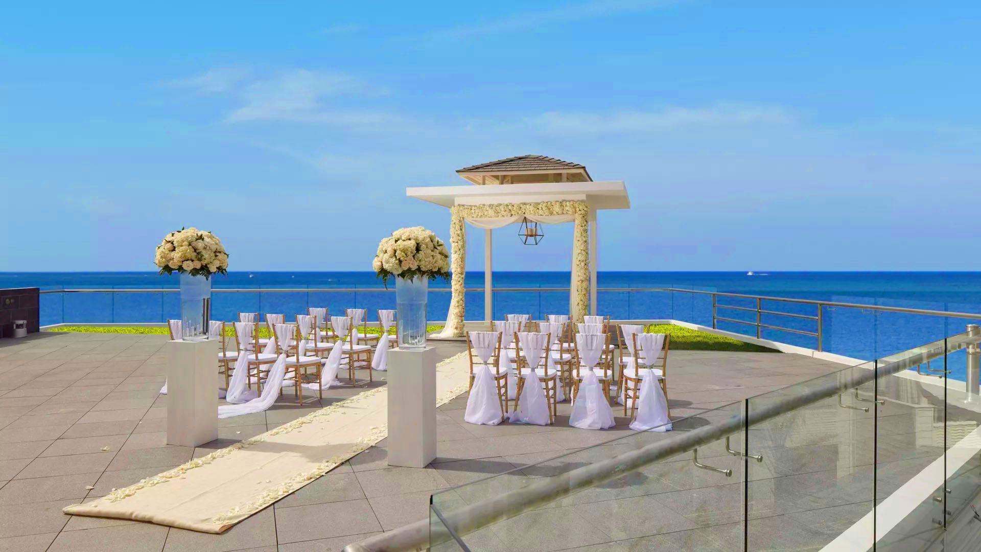 A Group Of Tables With White Cloths And Flowers On Them By The Water