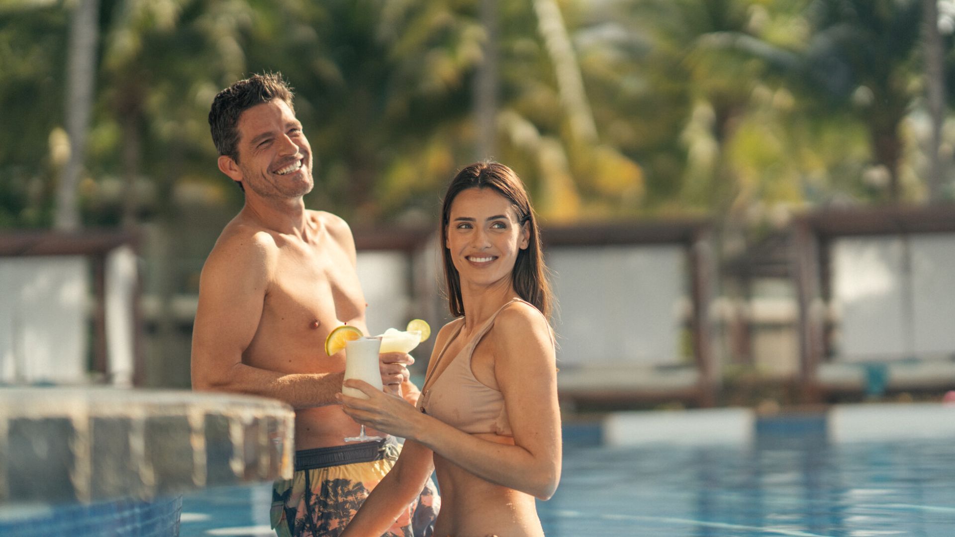 A Man And Woman In Swimsuits By A Pool
